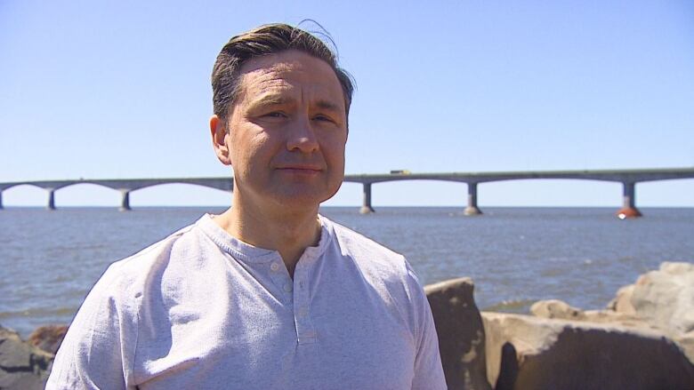 Man standing in front of large bridge.