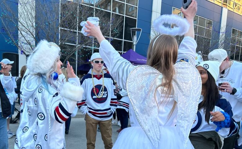 A woman in a white costume, dancing with another woman wearing an angel costume.