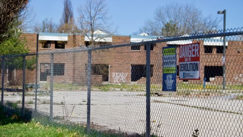 danger sign on fence with empty buildings in background