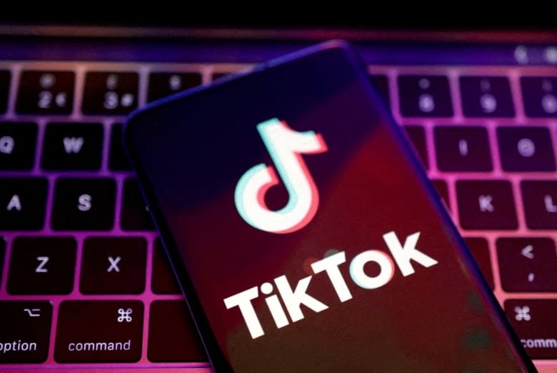 The app logo of TikTok is seen on a cellphone that is resting on a computer keyboard.