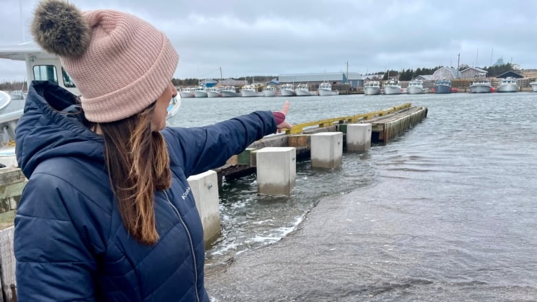 Woman with pink toque pointing to water.