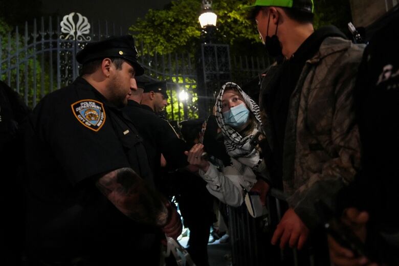 A person wearing the Palestinian keffiyeh talks with police officers as the police maintain a cordon around Columbia University where students barricaded themselves as they continue to protest in support of Palestinians, despite orders from university officials to disband or face suspension, during the ongoing conflict between Israel and the Palestinian Islamist group Hamas, in New York City, U.S., April 30, 2024.