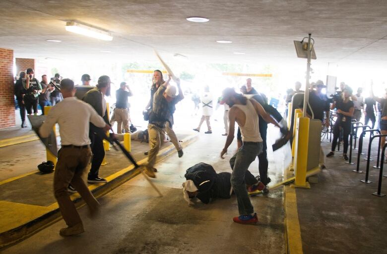 Several men are shown above a man supine on the ground, some wielding weapons.