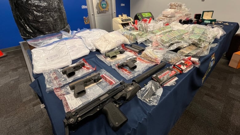 Cash, guns, drugs are set on display on a table