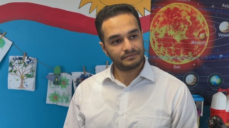 A man stands in front of a poster with the planets of the solar system on it.