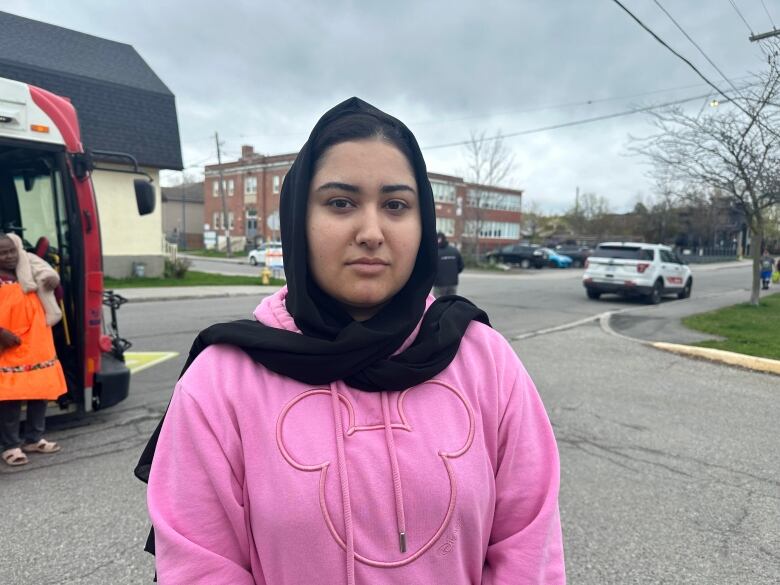 A woman in a pink hoodie and headscarf.