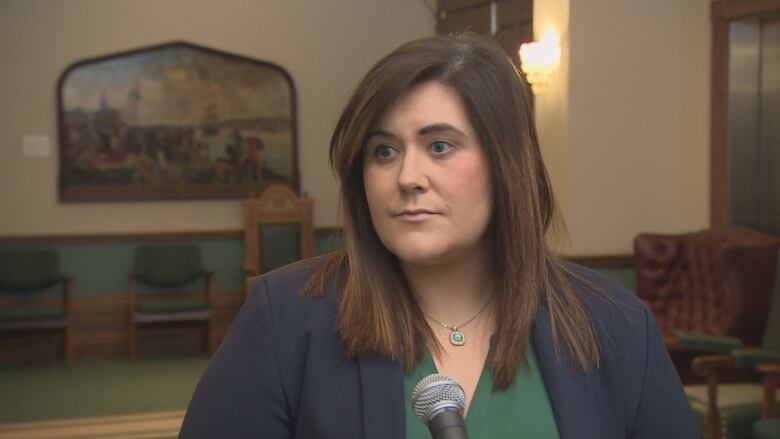 A woman wearing a green shirt and blue blazer stands inside Confederation Building in St. John's.