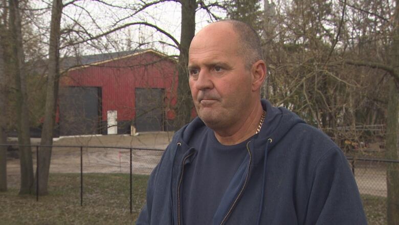 A man standing in a yard, with a garage in the background.