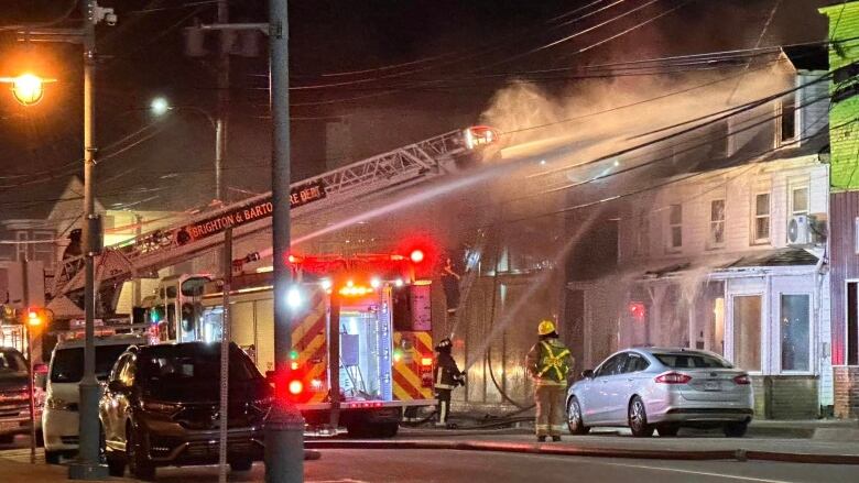 A fire truck sprays water on a three-storey white building.