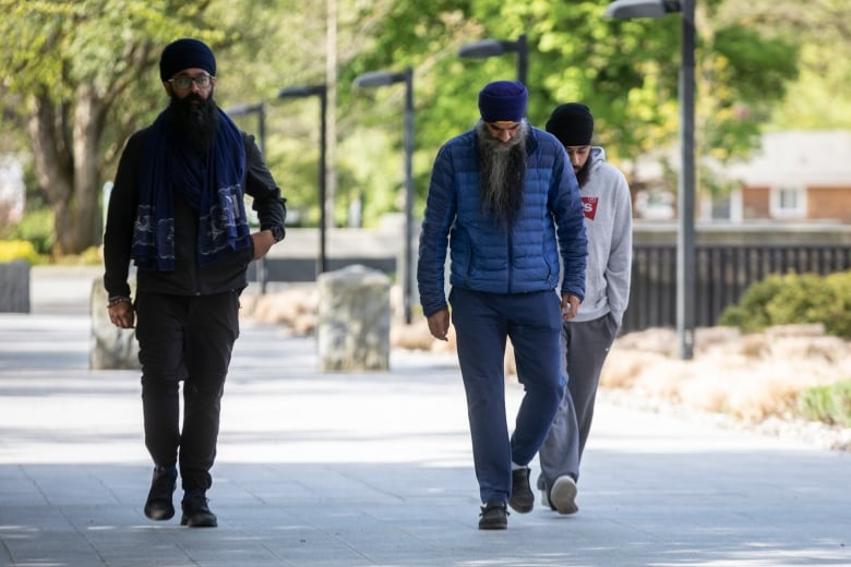 Moninder Singh, Bhupinder Singh Hoti and a family member walk into the RCMP 'E' division headquarters in Surrey, B.C on Friday May 3, 2024. 