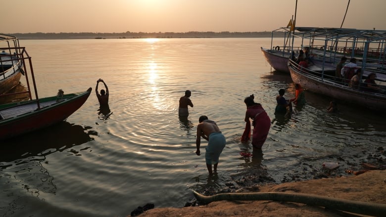 People bathe in the waters of a river at dawn.