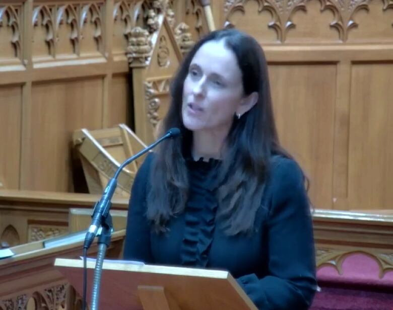 A woman wearing a black dress delivers a message in a church.