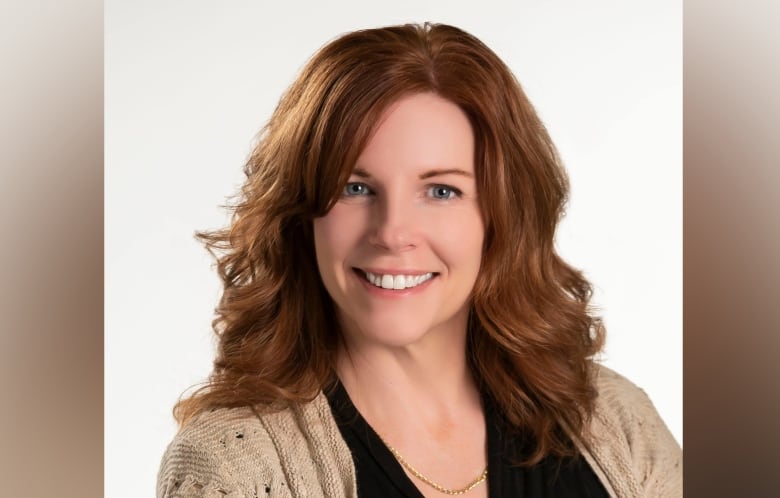 A woman smiles at a camera in a posed professional portrait.