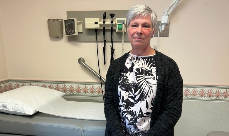 A woman stands in a medical examination room.