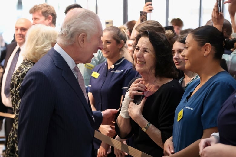 A person talks with people standing in a line.