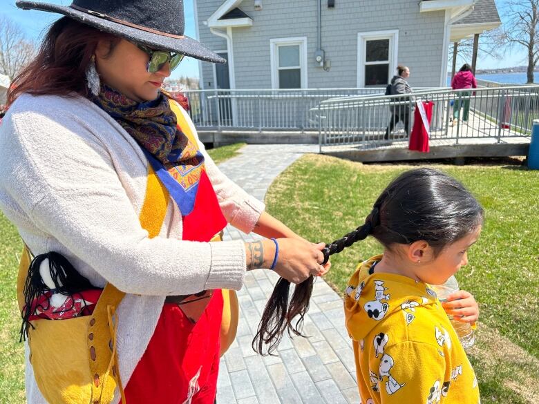 Woman braids girl's hair.