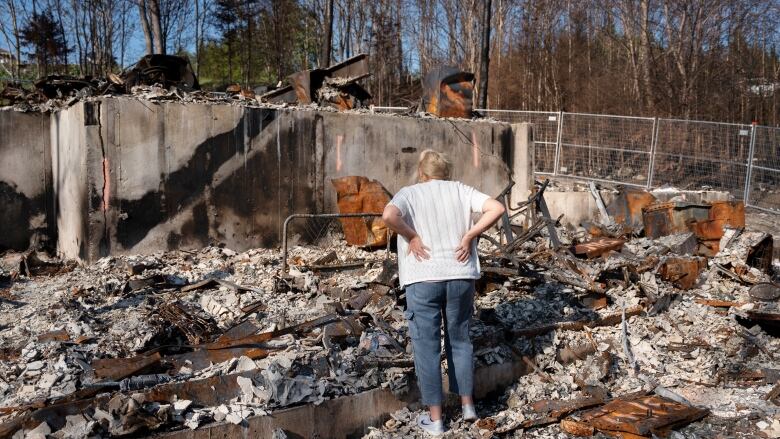 woman looks at burned down home