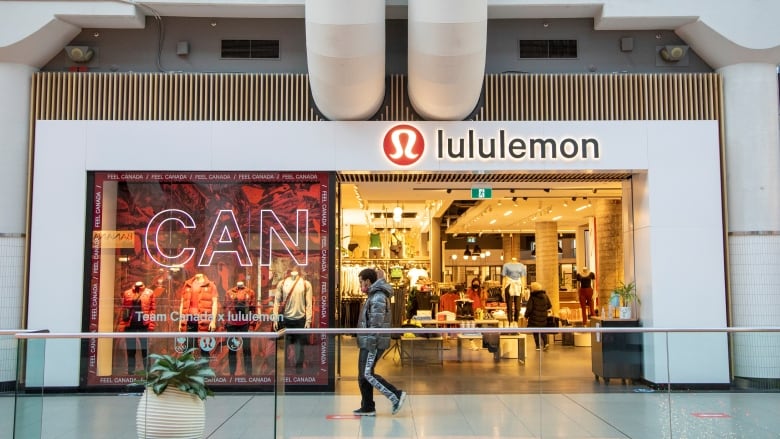 A person walks by a Lululemon clothing store in a shopping mall.