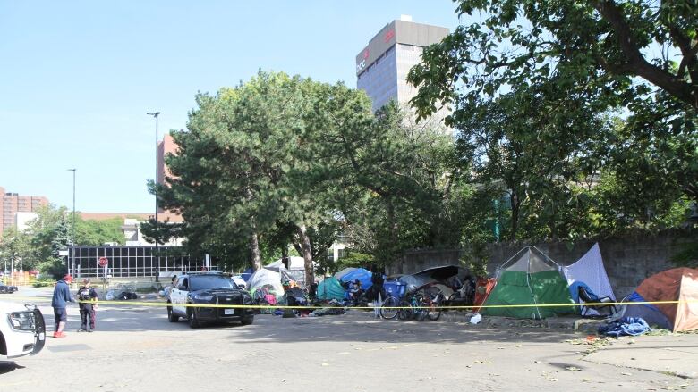 A group of tents in a parking lot cordoned off with police tape.