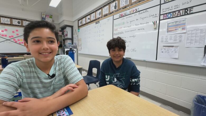 Two boys sit at desks