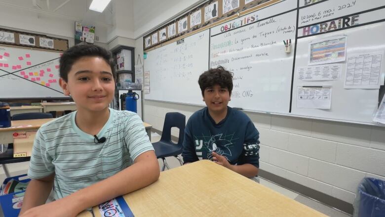 Two boys sit at desks