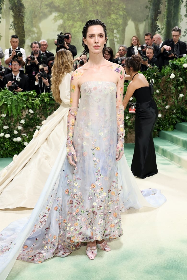 Rebecca Hall on the Met Gala red carpet wearing a floral dress with an extra-long train and sheer floral gloves