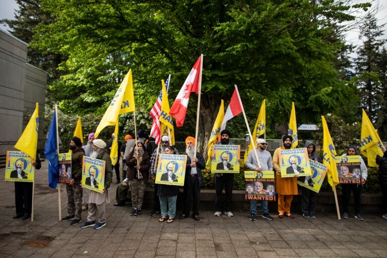 People carrying signs and flags stand in a row