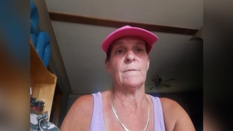 A woman looks at the screen wearing a baseball hat. 