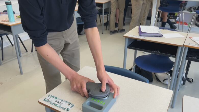 A student places his Yondr pouch against a special magnet, designed to unlock the phone from the pouch.