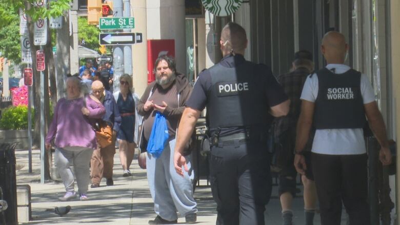 A police officer walks down a busy city street.