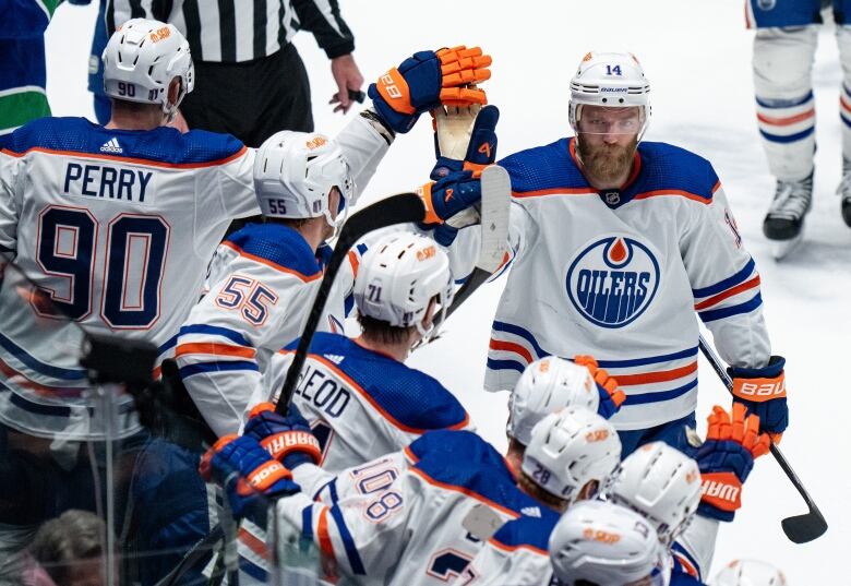 A hockey player high-fives teammates on a bench.