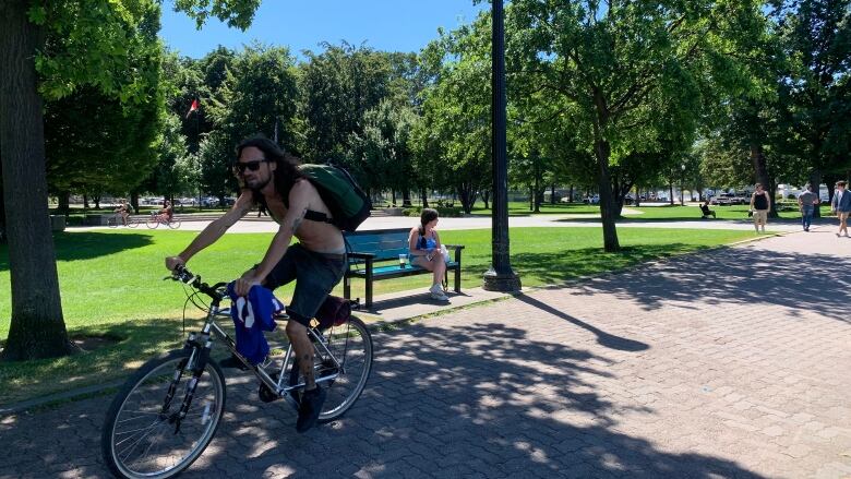 A shirtless man cycles through a park in Kelowna