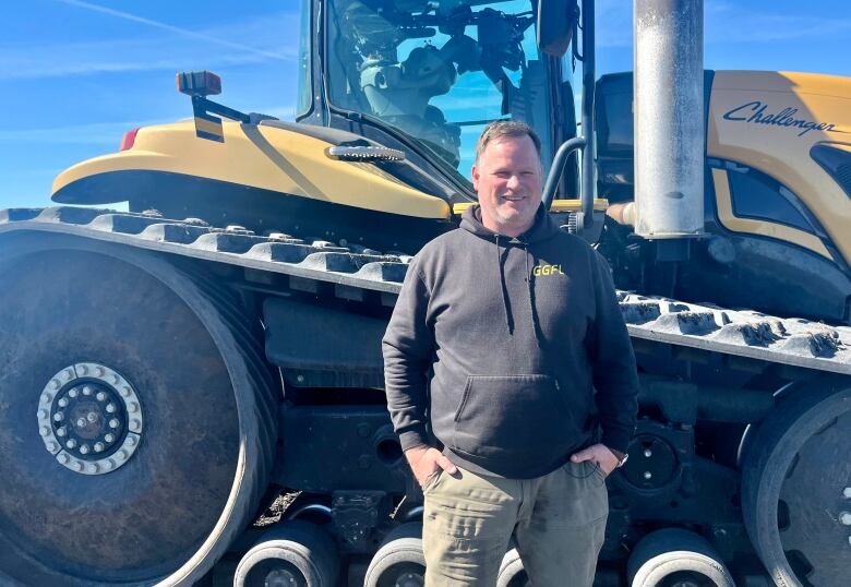 A man standing in front of a tractor.