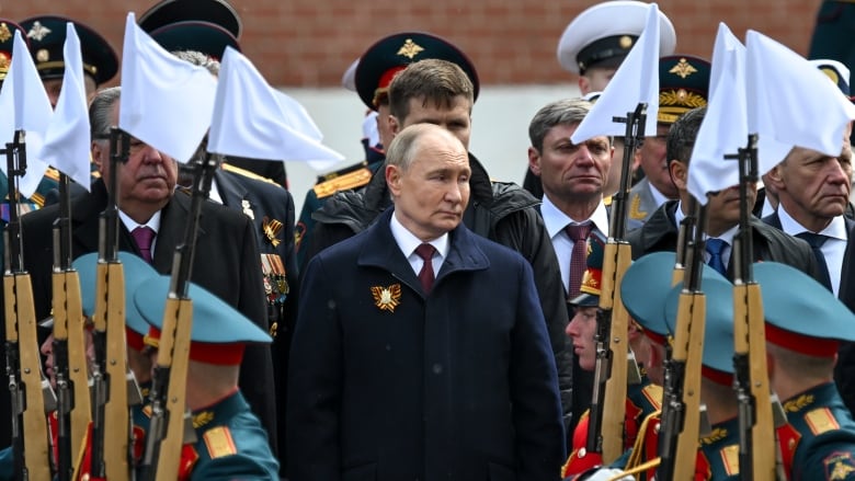 A man inspects soldiers in ceremonial uniforms.