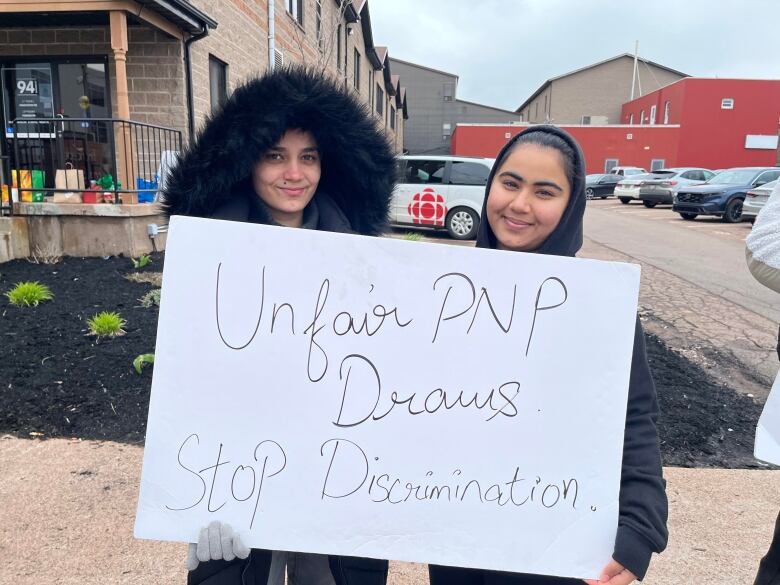 Two women hold a sign.