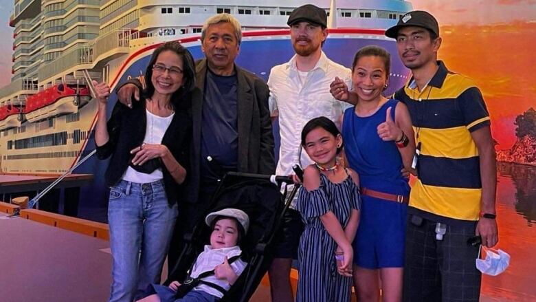 A family of seven stands in front of a mural of a cruise ship.