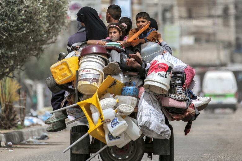 People sit with their belongings while riding in the back of a tricycle.