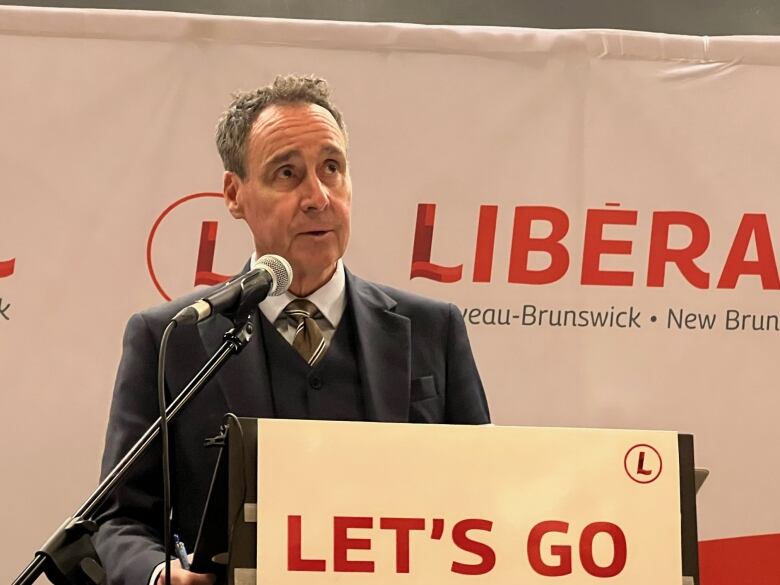 A man stands in front of a Liberal sign.