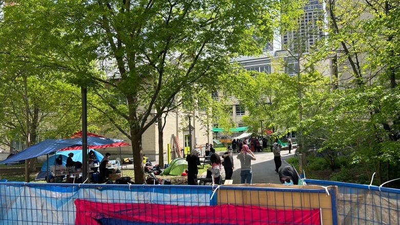 people setting up tents on the UQAM campus behind a blue gate