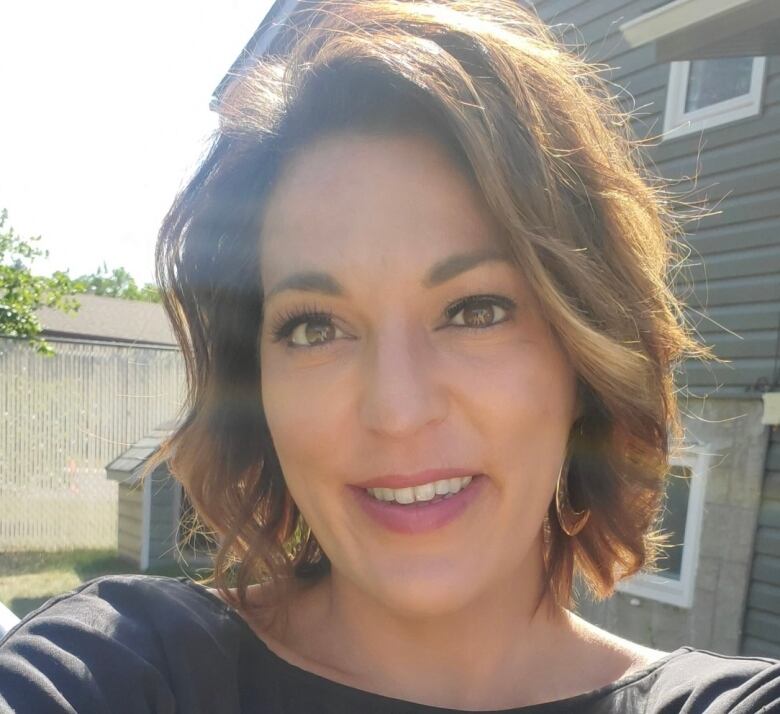 Selfie of woman standing in backyard in front of house.