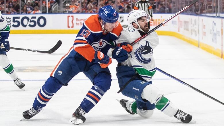 Two hockey players vie for a loose puck.