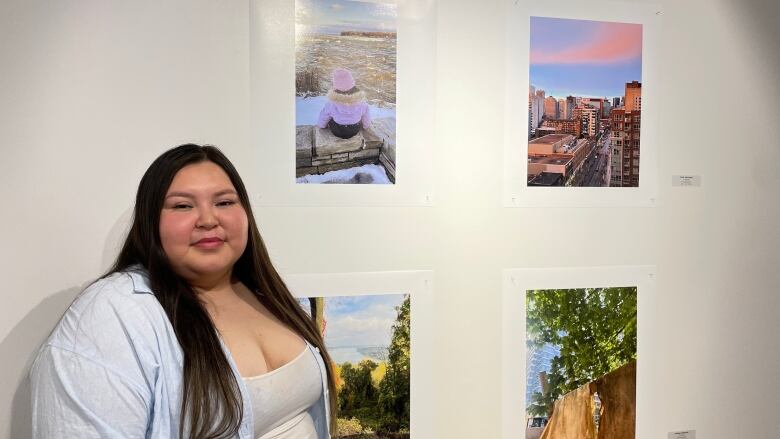 A women standing in front of her artwork, which is a picture of Montreal's high buildings. 