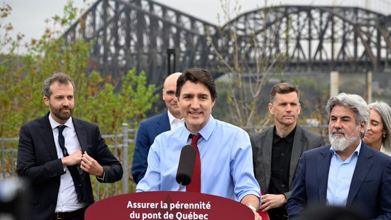 Men standing in front of bridge.