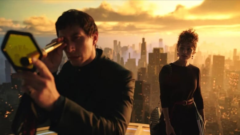 A man holds a spyglass to an octagonal piece of yellow glass. Behind him a woman stands, looking at him. They both appear to be standing on top of a skyscraper with a sprawling cityscape behind them. 