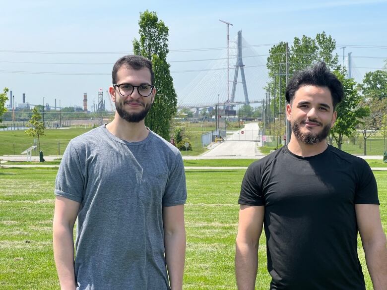 Two men stand in front of the bridge