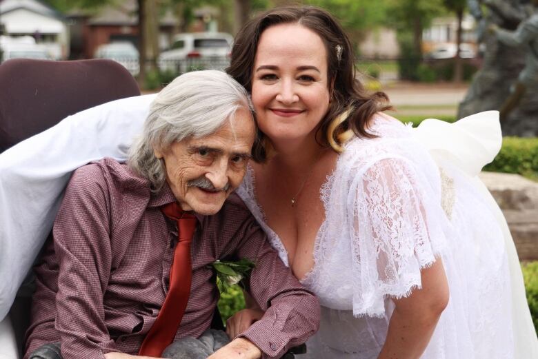 A woman in a wedding dress with her elderly father.