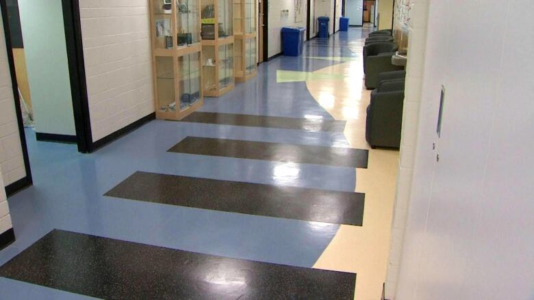 A blue hallway floor that has four large black bars painted across it.