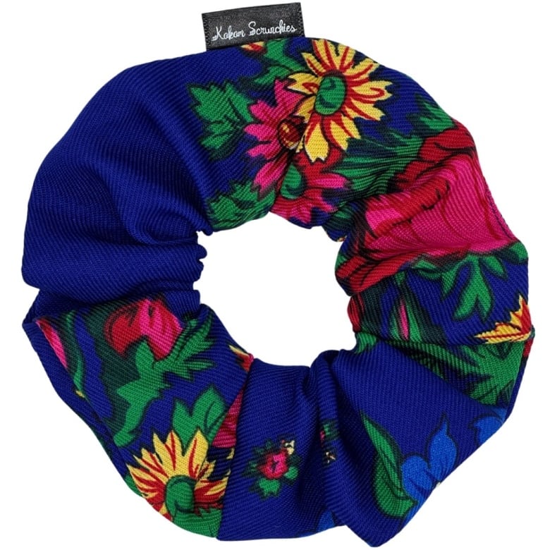 A blue scrunchie with a pattern of red and yellow flowers and green stems and leaves.