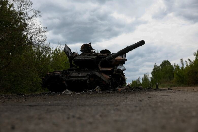 A destroyed tank is seen on a road in Ukraine's Kharkiv Region.