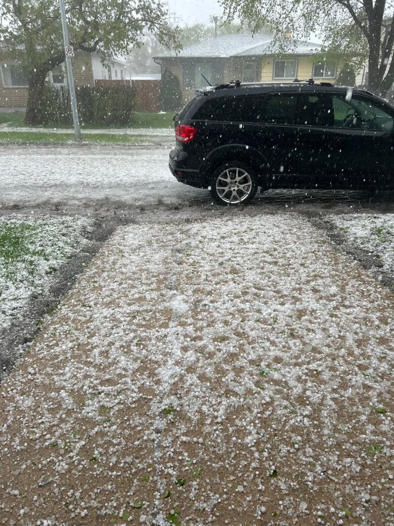 Hail falls and accumulates on a driveway.